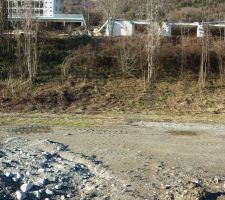 Notre terrain vu depuis le bord de la route d'acc&egrave;s. 
Il va jusqu'au sommet du talus. Le b&acirc;timent juste derri&egrave;re &agrave; droite va &ecirc;tre ras&eacute; et le grand immeuble en haut &agrave; gauche va subir une r&eacute;novation compl&egrave;te.