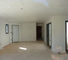 Vue du salon sur la porte d'entrée, avec le patio à droite qui donne pas mal de lumière