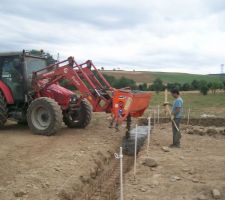 Grâce à notre tracteur équipé d'un godet malaxeur, on coule le béton des fouilles.