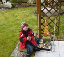 Hugo exposant ses cadeaux de Pâques découverts dans le jardin de mamy et papy