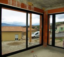 Vue de l'intérieure de la grande baie vitrée du salon, et de la porte fenêtre avec partie fixe.