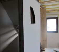 Le panneaux pour le plasma cachant l'escalier et le coin bureau
