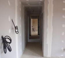 Couloir desservant les deux chambres des enfants à gauche, la chambre des parents, les WC et la salle d'eau à droite, puis le garage et la buanderie au fond