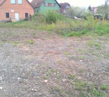 Le terrain nu, avec des piquets symbolisant la zone à creuser pour le terassement.
