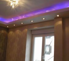 Finition des murs par la pose de 2 sortes de papiers peints intissés. (encollage direct sur le mur) Pose d'un lustre doré avec du cristal et essais des lumières. la couleur violettes est obtenus avec les spots et le néon bleu qui fait le tour de la corniche. Il reste à poser les rideaux et à meubler la pièce. Mission accompli :-)