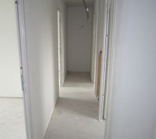Le dégagement du 1er étage avec à droite le futur placard, le bureau, l'escalier, la sde et les wc, et à gauche les portes des chambres 2 et 3.
