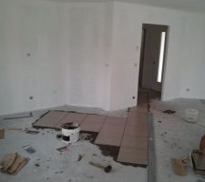 Début de la pose du carrelage par la porte d'entrée.