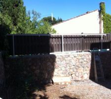 Fixation de la base la plus haute de l'abris.

Afin de ne pas poser tout le poids de la structure sur la brise vue en bois, nous avons fixé 3 poteaux sur le muret et poser l'abri dessus.