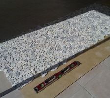 Pose à blanc des galets pour mur de la douche à l'italienne