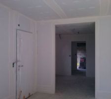 Vue du s&eacute;jour, l'enfilade cuisine, cellier, garage. Une porte coulissant 2 vantaux est pr&eacute;vue en s&eacute;paration du s&eacute;jour