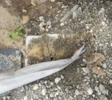 Le petit cadeau caché. Le tampon du regard cassé dissimulé sous le géotextile.