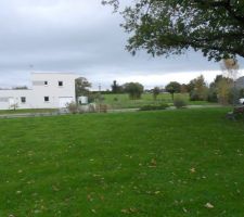 Vue du terrain avec un plan plus large.
On peut voir la maison cubique des voisins (&agrave; droite). La maison du c&ocirc;t&eacute; gauche est masqu&eacute;e par une haie bien dense.