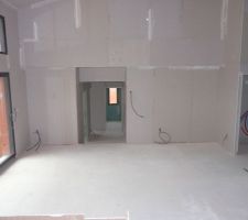 Vue de la cuisine sur le salon, le hall d\'entrée, et l\'escalier du couloir de l\'espace enfants et bureau.