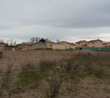 Prise de vue du terrain, il va de mon homme (qui on dirait pas comme sa hein mais il a froid) jusqu'a la maison derriere qui n'est pas crepis