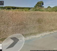 Photo du terrain vue de la rue, avec le talus qui doit être décaissé pour faire le chemin d'accès jusqu'à l'implantation de la maison.